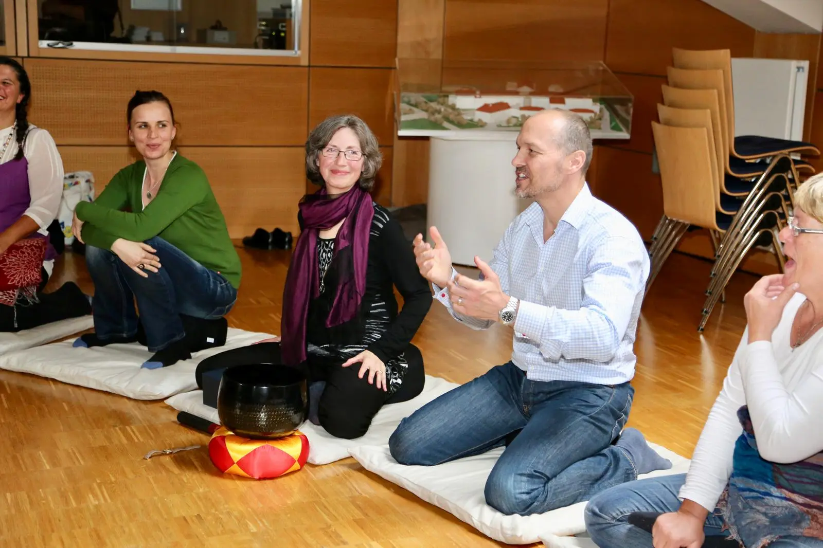 Dieter Schleier spricht sitzend zu einer Meditationsgruppe, vor ihm eine Klangschale